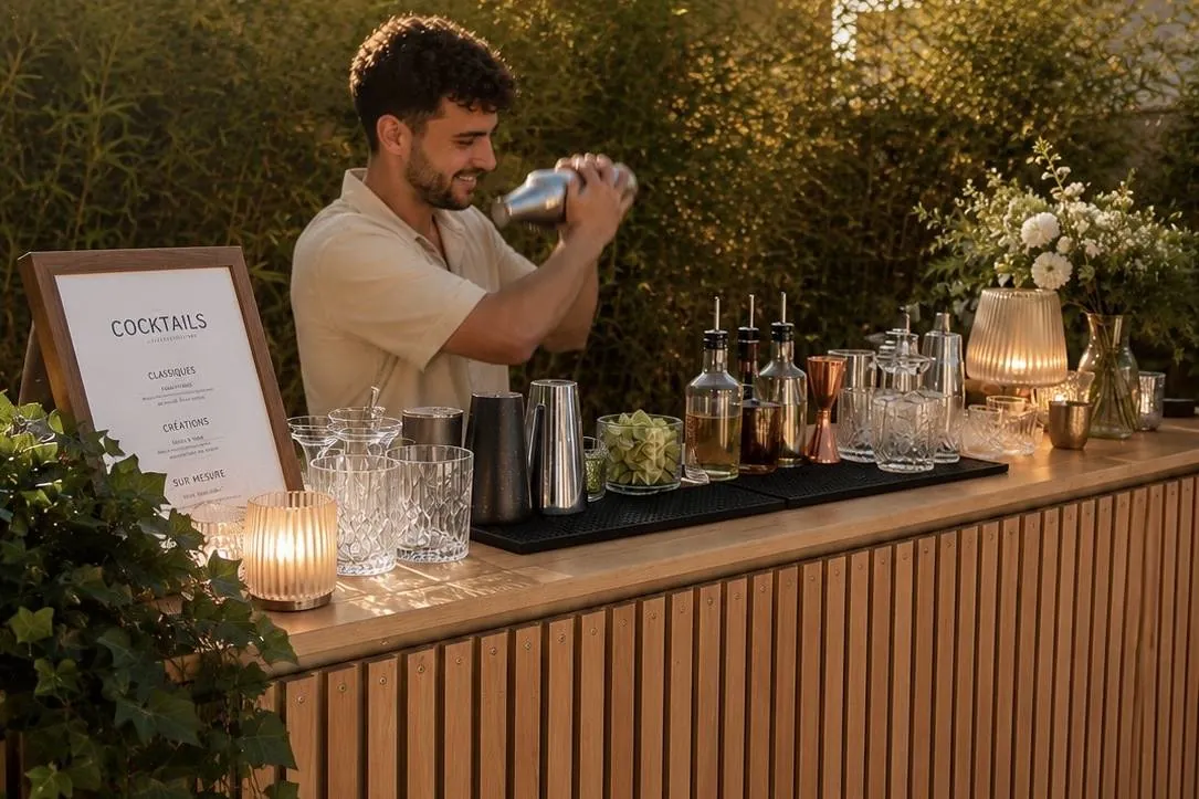 Bar mobile Hope installé en extérieur : comptoir en bois, carte des cocktails et barman au shaker